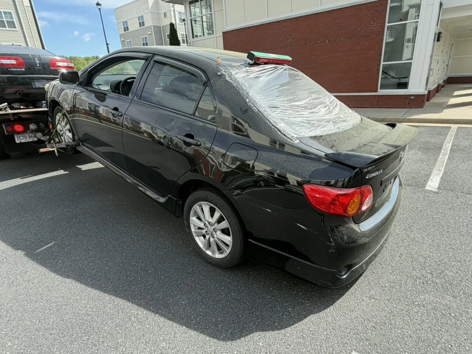 Damaged Toyota Corolla being picked up by Dalo Auto Recycling in a Centreville, VA apartment community