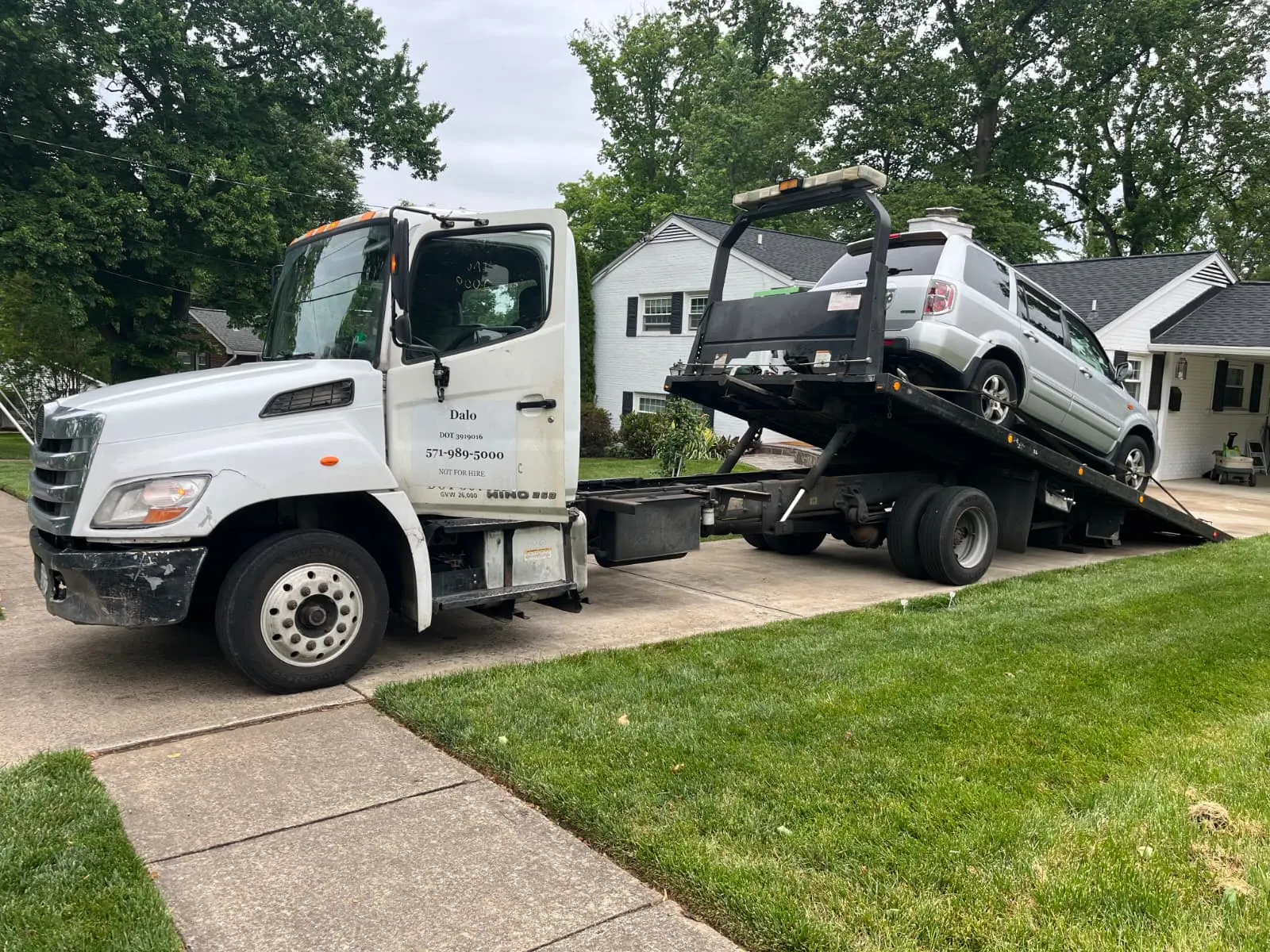 Dalo Auto Recycling flatbed truck picking up a vehicle from a residential driveway in Dumfries, VA