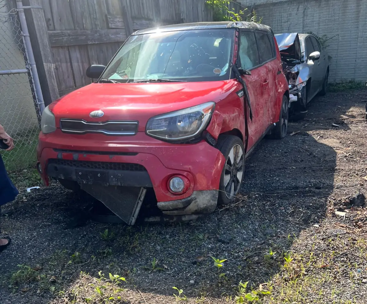 A wrecked red 2017 Kia Soul with heavy front-end damage at a Northern Virginia tow yard, purchased by Dalo Auto Recycling