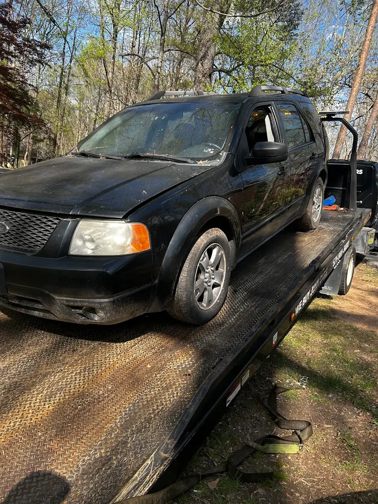 Older SUV loaded onto a Dalo Auto Recycling flatbed truck in Woodbridge, VA